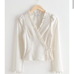 Tailored wrap top w/ accentuated waistline, ruffled detailing & puff shoulders.